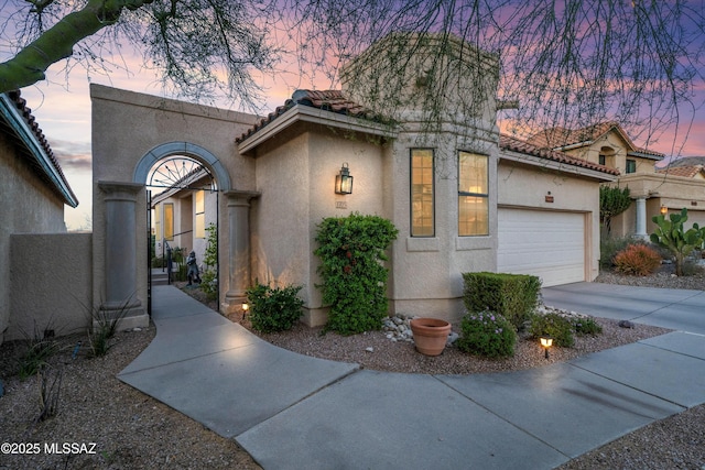 mediterranean / spanish-style home featuring stucco siding, a tile roof, and a garage