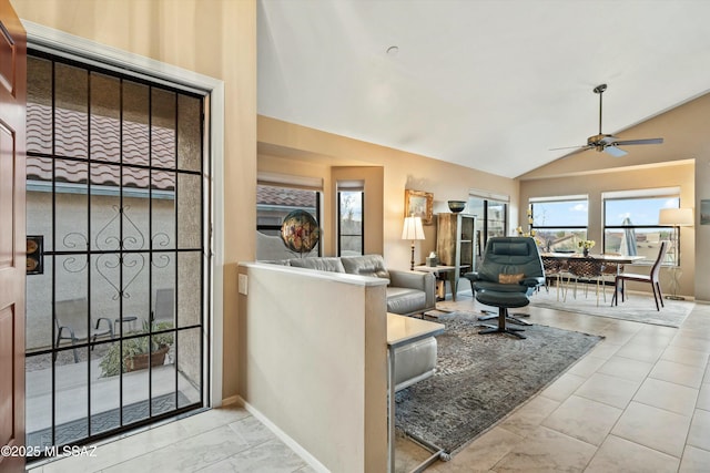 living room featuring baseboards, a ceiling fan, and vaulted ceiling