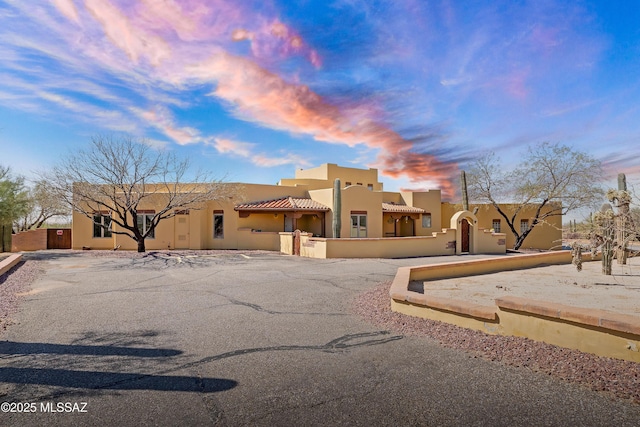 pueblo revival-style home featuring a tile roof and stucco siding