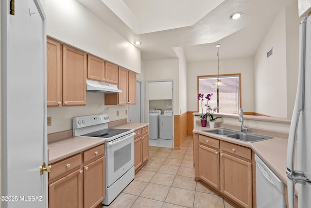 kitchen with white appliances, a sink, light countertops, under cabinet range hood, and washer and clothes dryer