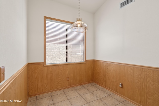 interior space featuring light tile patterned floors, a wainscoted wall, wood walls, and visible vents