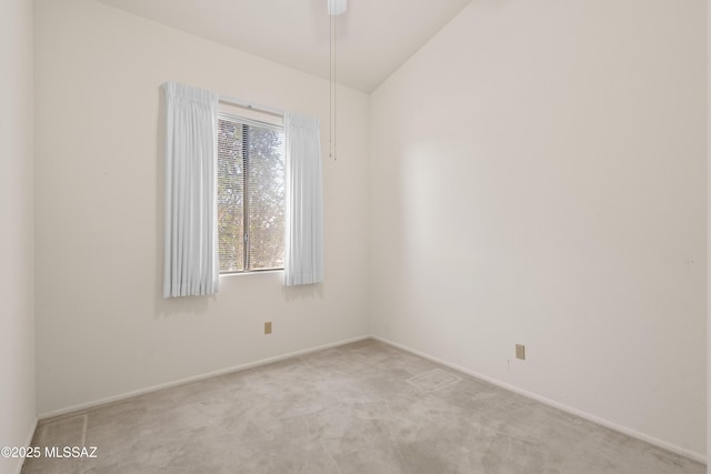 spare room featuring vaulted ceiling, baseboards, and light carpet