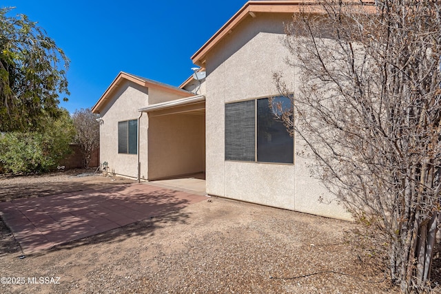 back of property with stucco siding, a patio, and fence