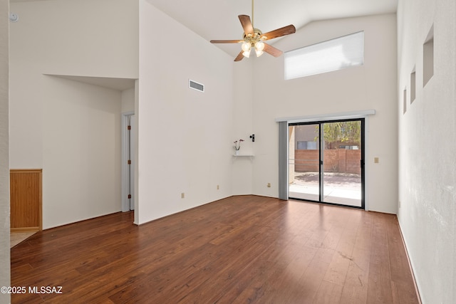 spare room featuring visible vents, a high ceiling, a ceiling fan, and hardwood / wood-style flooring