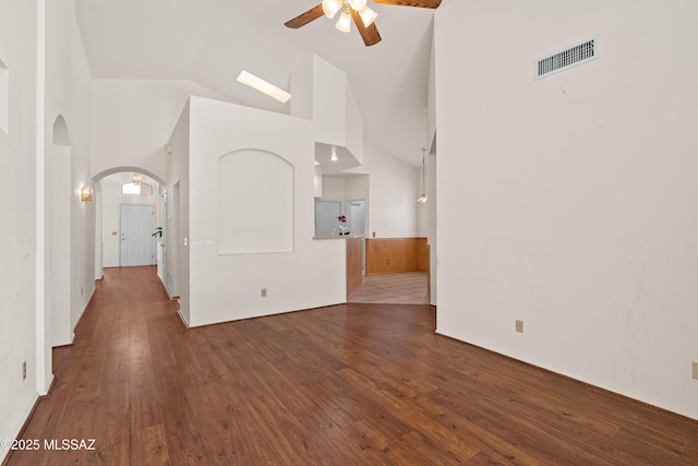 unfurnished living room featuring visible vents, high vaulted ceiling, hardwood / wood-style flooring, arched walkways, and ceiling fan