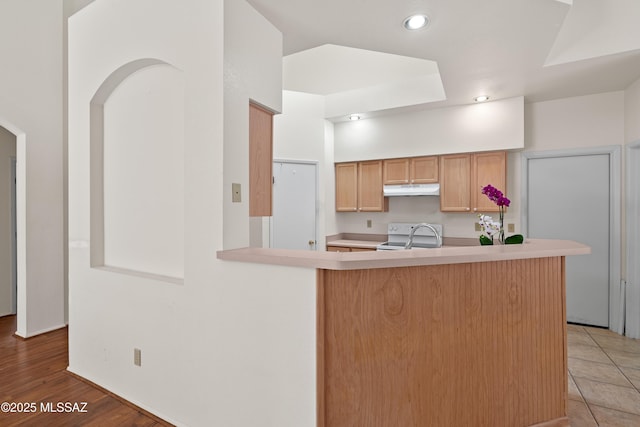 kitchen with under cabinet range hood, white electric range, a sink, recessed lighting, and light countertops