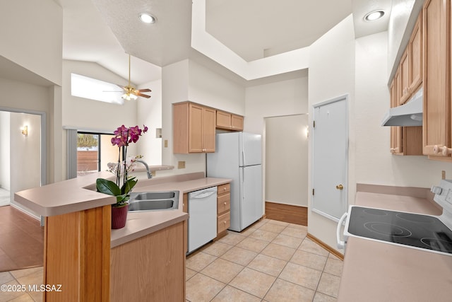 kitchen featuring under cabinet range hood, light countertops, a peninsula, white appliances, and a sink