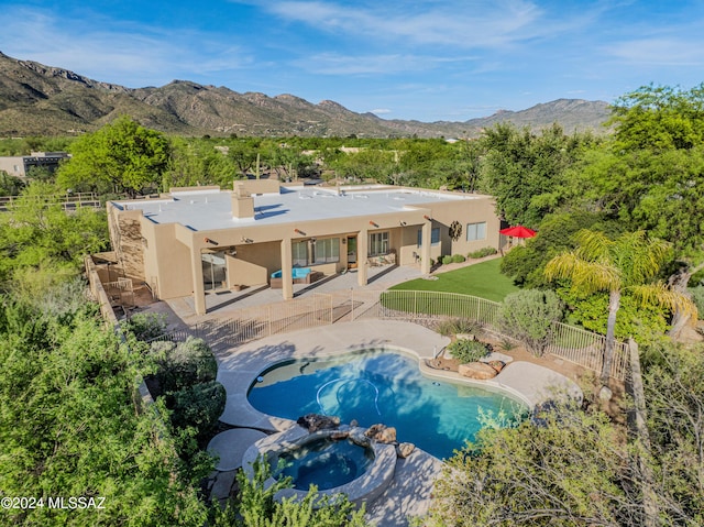 back of house with a pool with connected hot tub, stucco siding, a fenced backyard, a patio area, and a mountain view