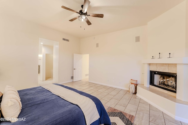 bedroom featuring visible vents, baseboards, a tiled fireplace, light tile patterned flooring, and a ceiling fan