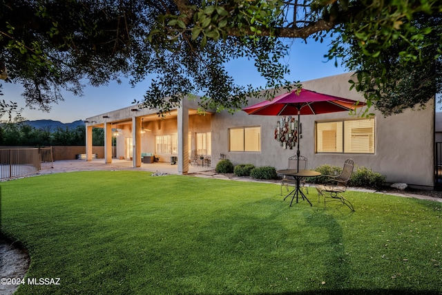 rear view of property featuring a yard, a patio, and fence