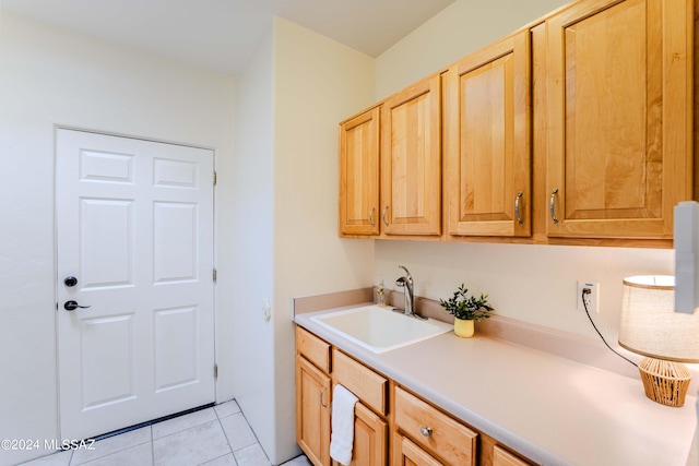 laundry area with light tile patterned flooring, cabinet space, and a sink