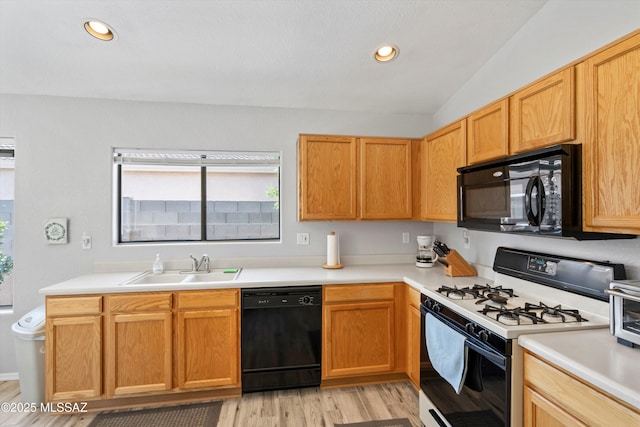 kitchen featuring recessed lighting, a sink, black appliances, light countertops, and light wood-style floors