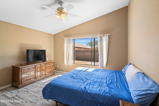 bedroom with a ceiling fan, vaulted ceiling, baseboards, and light wood-type flooring