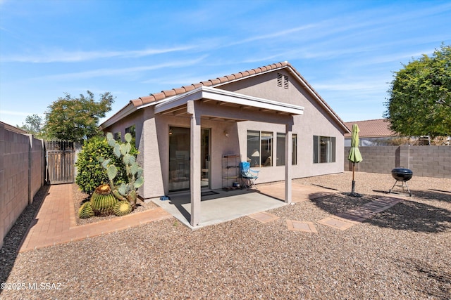 rear view of property featuring a patio area, stucco siding, and a fenced backyard