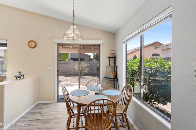 dining area with light wood finished floors, baseboards, and vaulted ceiling