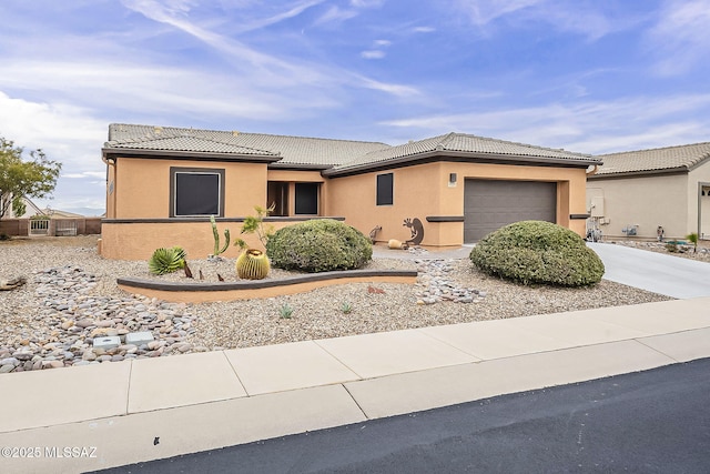 view of front of house featuring a tiled roof, a garage, driveway, and stucco siding