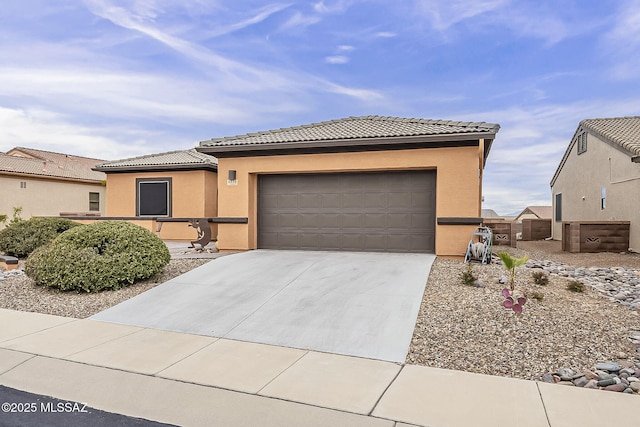 prairie-style house with stucco siding, concrete driveway, a tile roof, and a garage