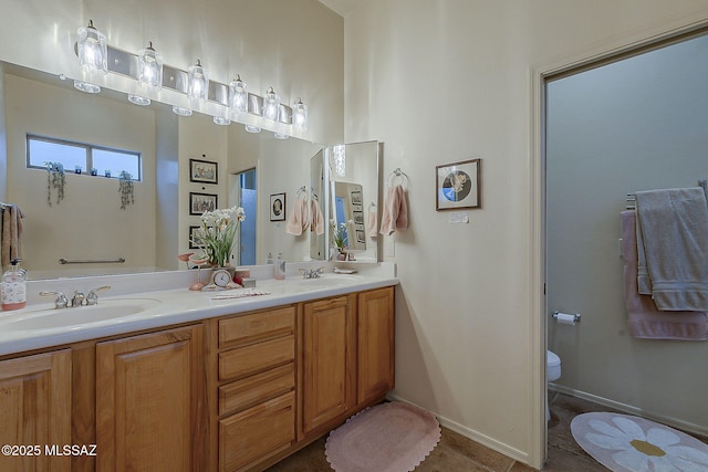 full bathroom featuring double vanity, tile patterned floors, toilet, and a sink