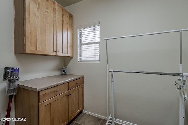 washroom with dark tile patterned floors and cabinet space