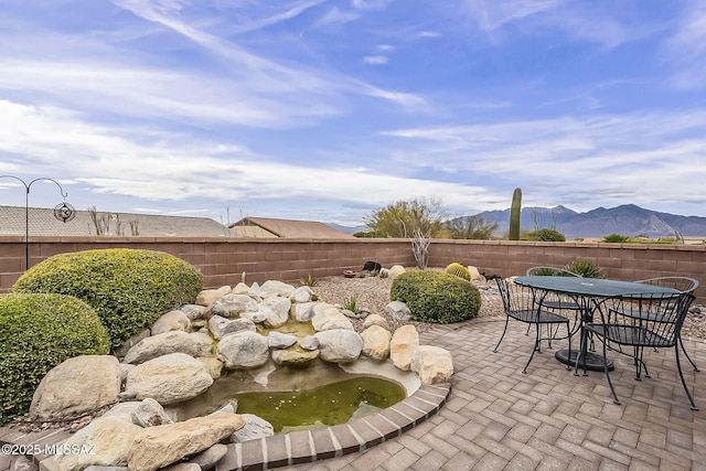 view of patio / terrace featuring outdoor dining space, a fenced backyard, and a mountain view