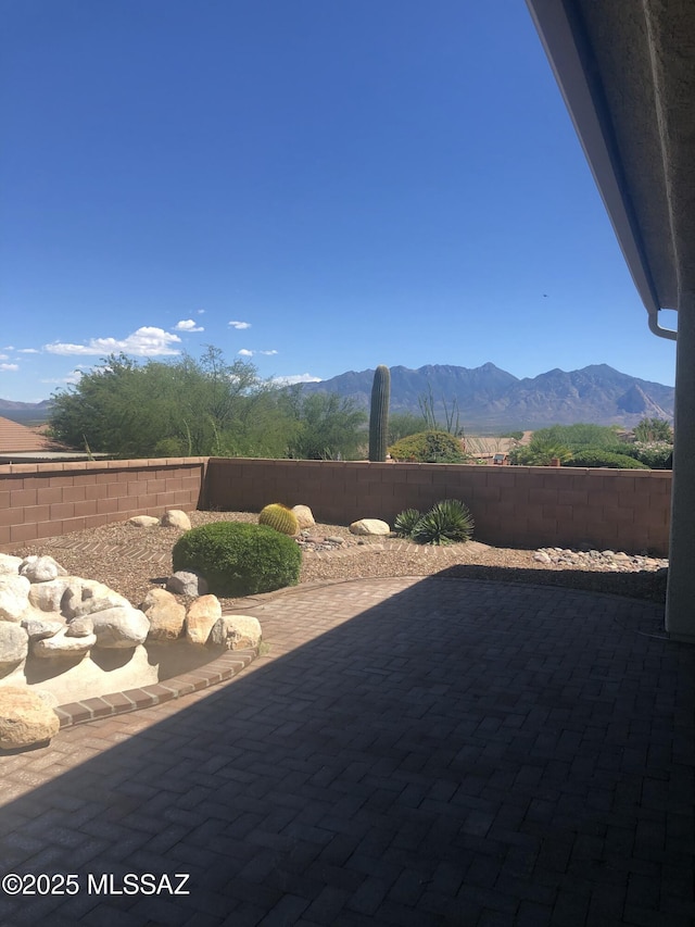 view of patio with a mountain view and a fenced backyard