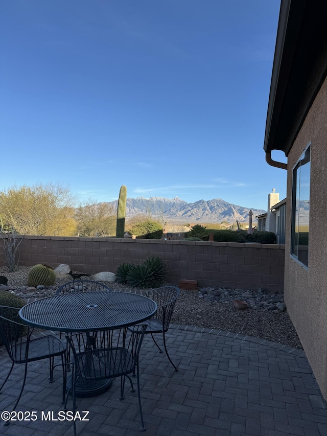 view of patio with outdoor dining area, fence, and a mountain view