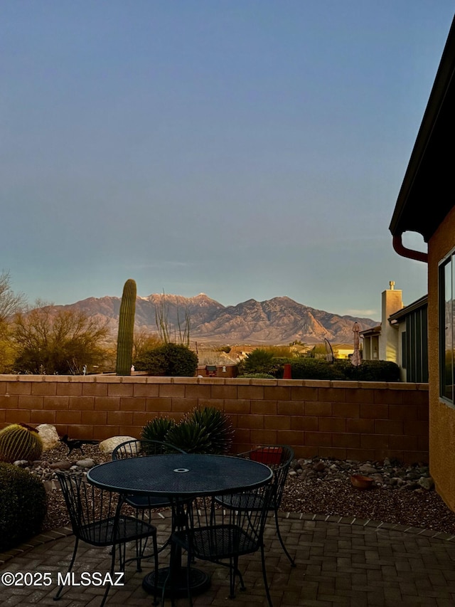 view of patio featuring outdoor dining area, fence, and a mountain view