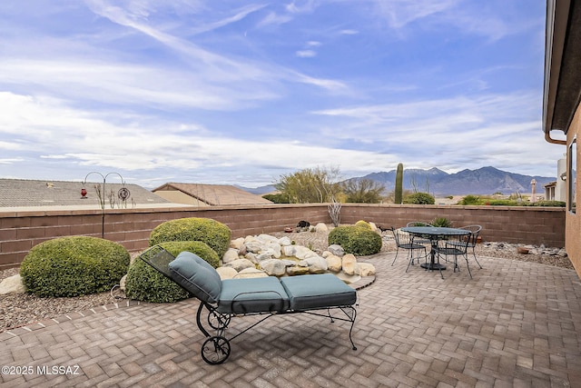 view of patio / terrace featuring outdoor dining space, fence private yard, and a mountain view