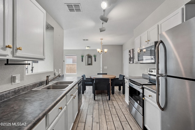 kitchen with wood finish floors, visible vents, appliances with stainless steel finishes, and a sink