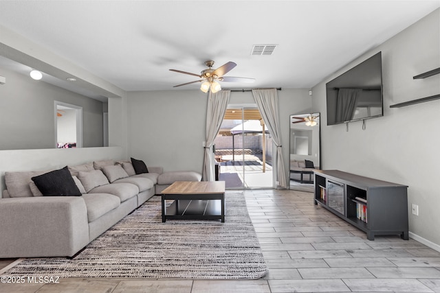 living area featuring light wood-style floors, a ceiling fan, visible vents, and baseboards