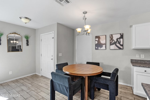 dining space with light wood-style flooring, baseboards, visible vents, and a chandelier