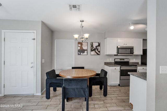 dining room featuring wood tiled floor, baseboards, visible vents, and a chandelier