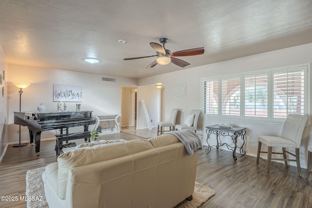 living area with visible vents, baseboards, wood finished floors, and a ceiling fan