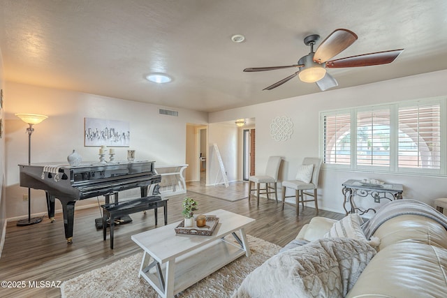 living area featuring wood finished floors, a ceiling fan, visible vents, and baseboards