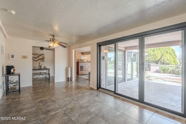 interior space with a textured ceiling and a ceiling fan