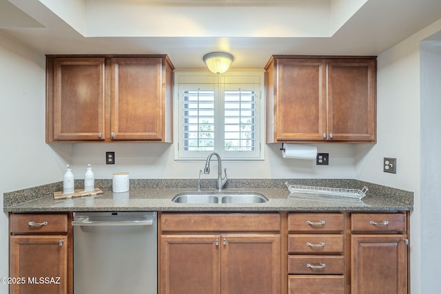 kitchen featuring dark stone countertops, dishwasher, brown cabinets, and a sink