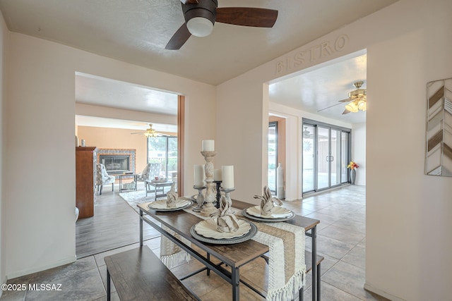 dining space featuring a glass covered fireplace and ceiling fan