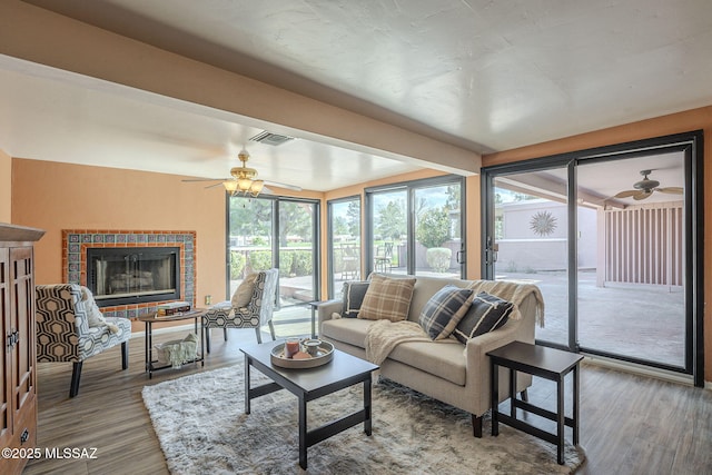 living room with visible vents, wood finished floors, and a ceiling fan