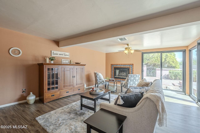 living area with wood finished floors, a brick fireplace, baseboards, and visible vents