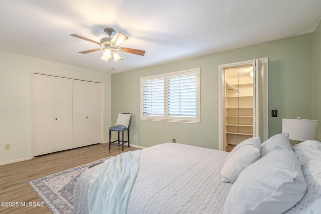 bedroom with a closet, baseboards, a ceiling fan, and wood finished floors