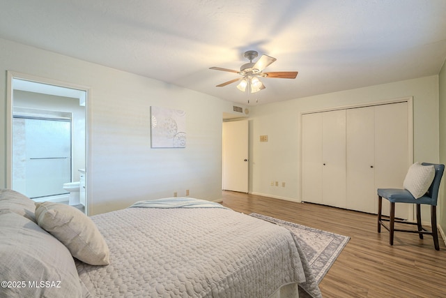 bedroom featuring visible vents, wood finished floors, a closet, ensuite bath, and a ceiling fan