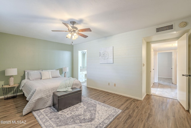 bedroom with visible vents, baseboards, ensuite bathroom, wood finished floors, and a ceiling fan