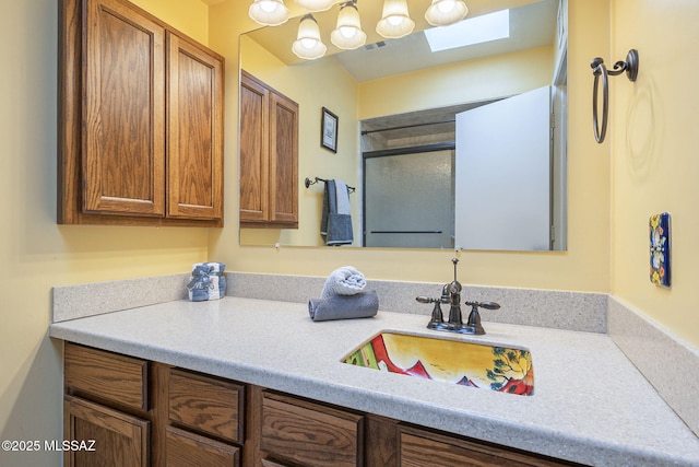 bathroom with a shower with door, visible vents, a skylight, and vanity