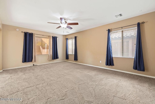 carpeted empty room with visible vents, baseboards, and a ceiling fan