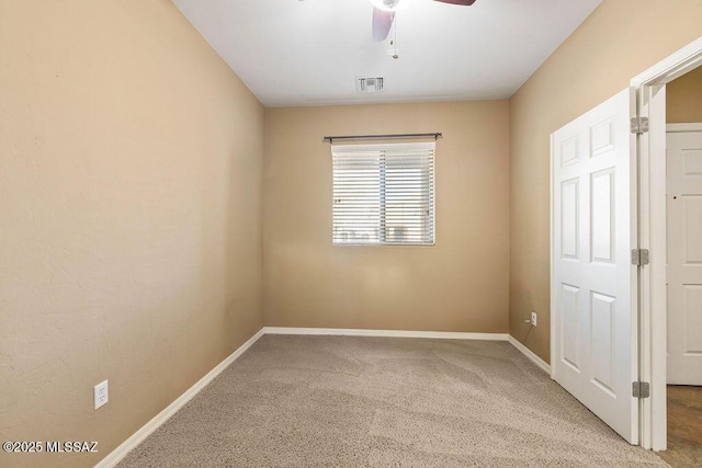 empty room with carpet, visible vents, baseboards, and ceiling fan