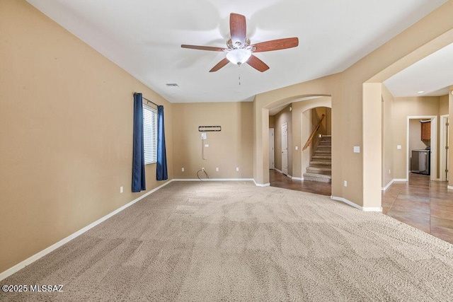 unfurnished room featuring visible vents, a ceiling fan, stairway, arched walkways, and carpet flooring