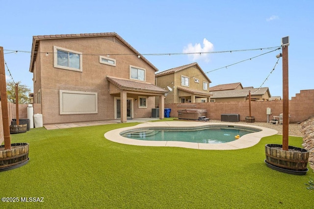 rear view of property with central air condition unit, a hot tub, a patio, a fenced backyard, and a lawn