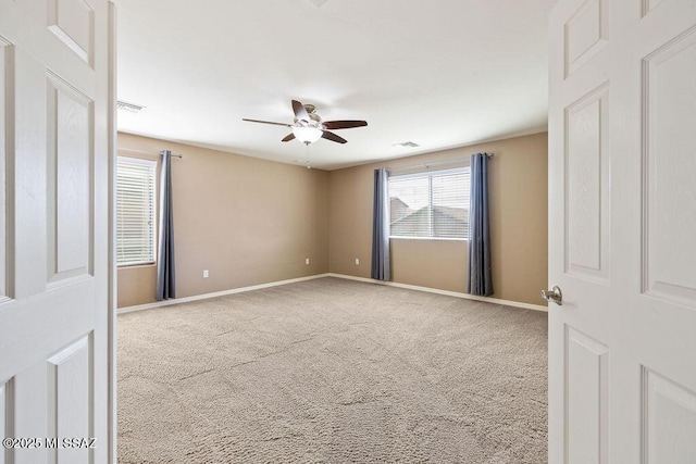carpeted spare room with visible vents, baseboards, and ceiling fan