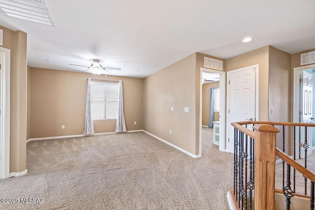 carpeted empty room with visible vents, baseboards, and a ceiling fan