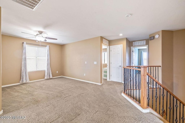 carpeted empty room featuring a ceiling fan, baseboards, and visible vents